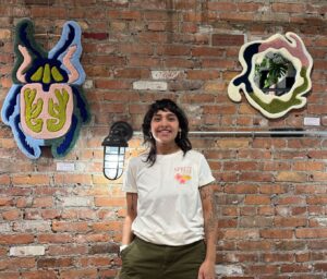 The artist standing between two fiber art pieces.